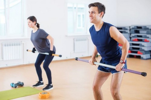 mand og kvinde træner ben med vægtstænger 