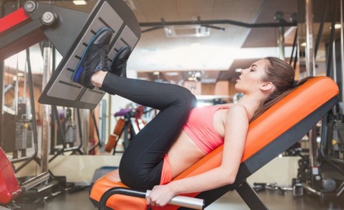 kvinde bruger træningsmaskine i fitnesscenter