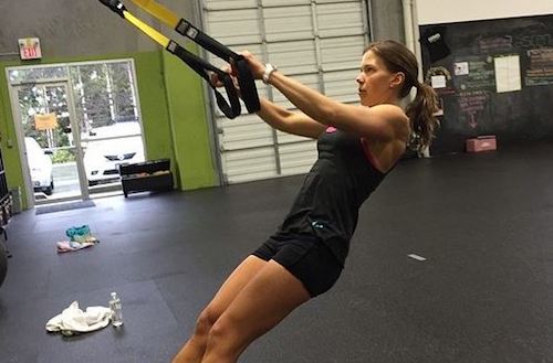 Kvinde der træner med trx i fitness