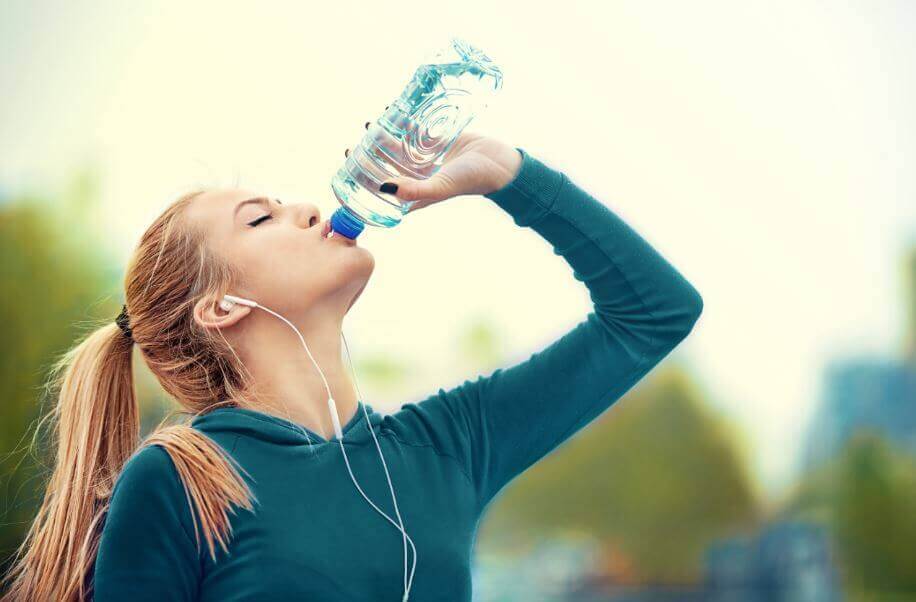 Kvinde drikker vand under træning for at forbrænde kalorier