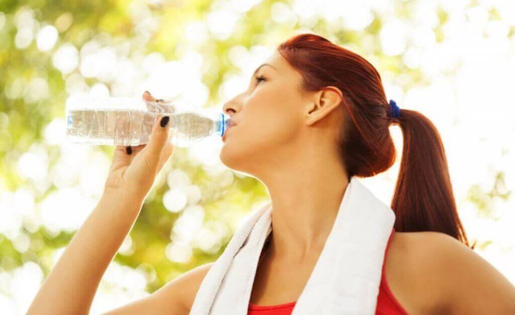 Kvinde drikker vand mens hun træner