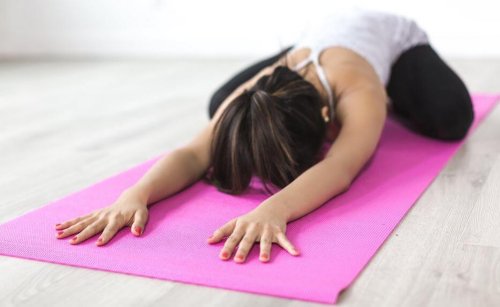 kvinde der laver yogaøvelse på en måtte