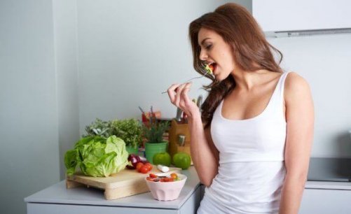 kvinde der spiser salat i køkken