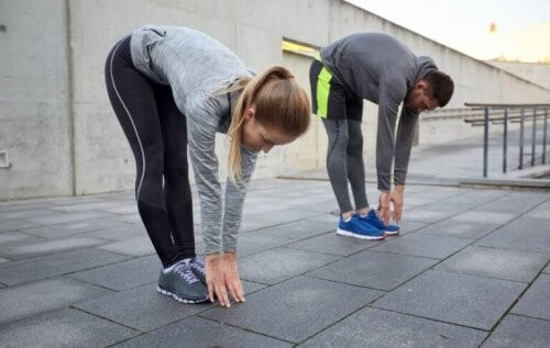 Kvinde og mand laver strækøvelser efter intens træning