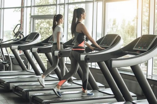 Kvinder går på løbebånd i fitnesscenteret 