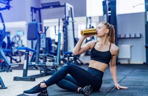 kvinde der drikker fra vanddunk i fitness