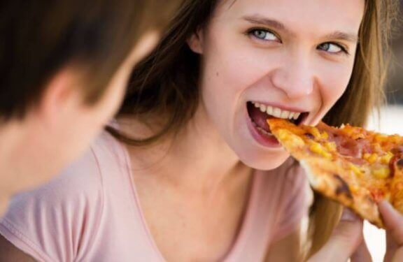 Pige spiser pizza, en ultraforarbejdet mad (UPF).