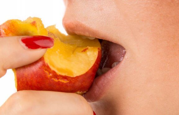 kvinde der spiser et stykke frugt