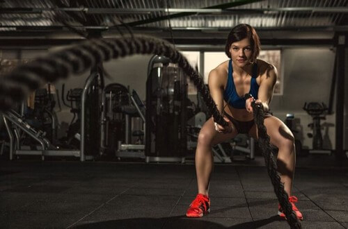 Kvinde udfører træningsøvelser med battle ropes