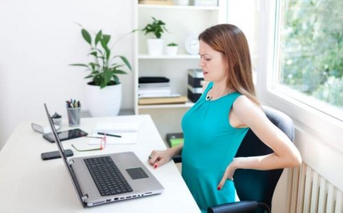 kvinde på kontor med rygsmerter