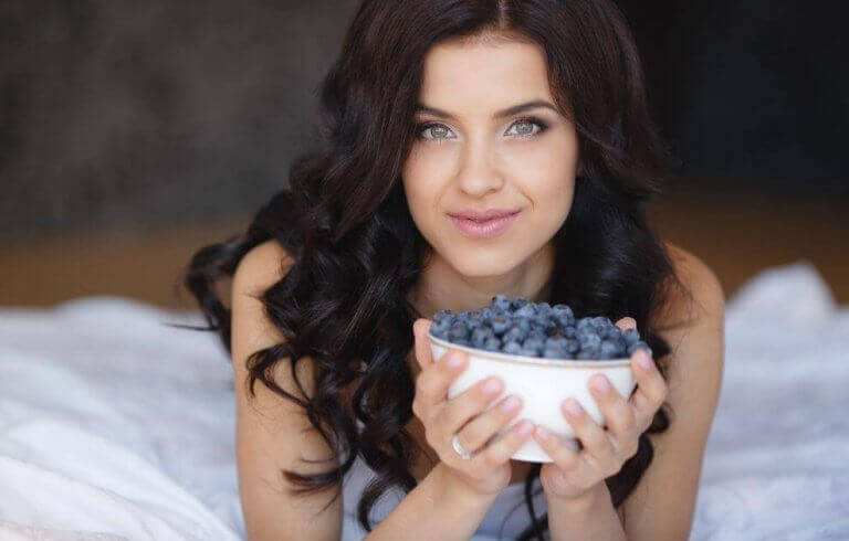 kvinde der holder en skål med blåbær