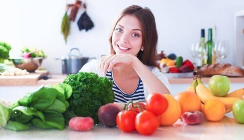 kvinde bag bord med frugt og grønt