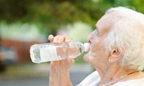 Ældre kvinde drikker en flaske vand