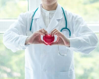 læge der former et hjerte med sine hænder