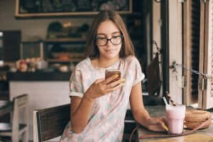 ung pige på café med sin telefon