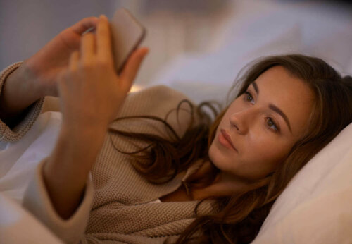 kvinde der kigger på sin mobil i sengen