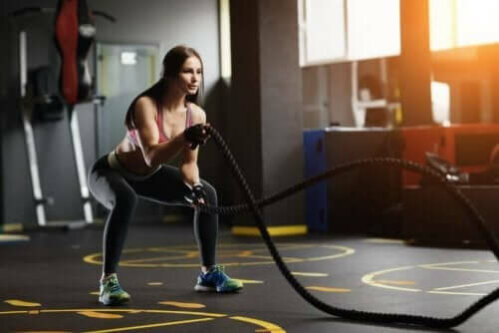 kvinde der træner med et battle rope