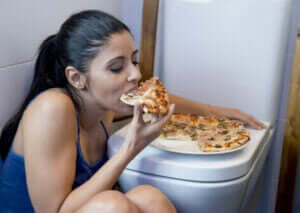 kvinde der spiser pizza på toilettet