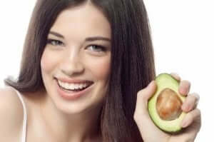 kvinde der holder en halv avocado