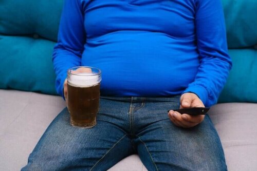 overvægtig mand med øl og fjernbetjening i hænderne