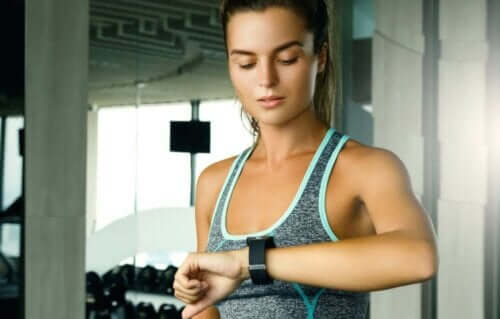 kvinde der kigger på sit ur for at undgå risici ved at træne for meget