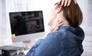 kvinde på kontor med ondt i nakken