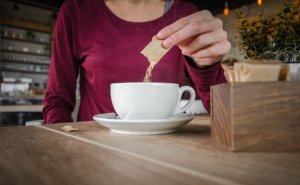 Une femme versant du sucre dans son café