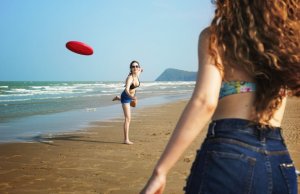 deux femmes qui jouent au frisbee à la plage.
