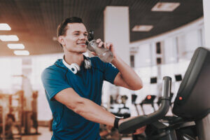 Un homme qui boit de l'eau pendant sa séance d'entraînement.