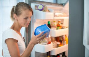 Une femme qui vérifie un aliment périmé au frigo.