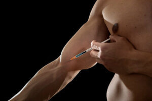 Un sportif qui s'injecte une substance dans le bras à travers une seringue. 