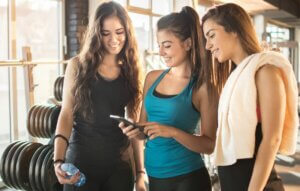 Trois jeunes femmes sportives qui regardent un téléphone. 