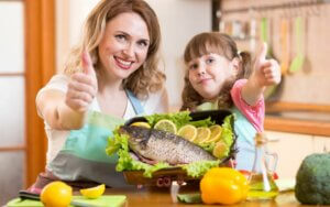 Une maman et sa fille devant un plat de poisson. 