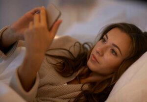Une femme au lit avec son téléphone.