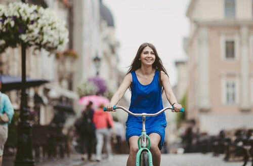 Ragazza con abito blu pedala in bici