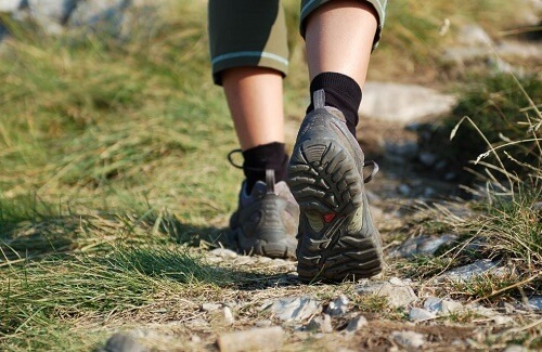 Ragazza cammina sull'erba indossando delle scarpe da trekking