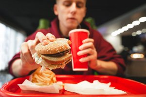 uomo che mangia hamburger in un fast food 