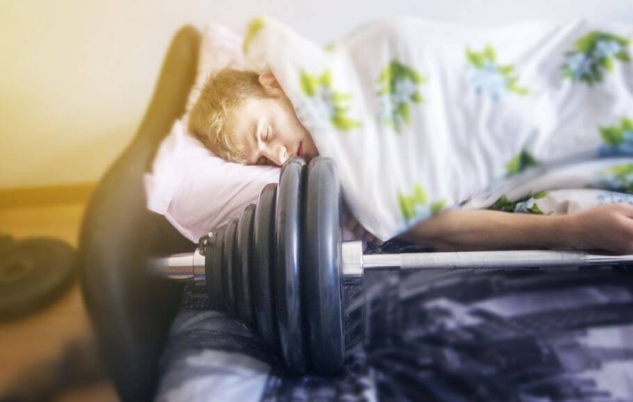 Atleta che dorme accanto a un bilanciere 