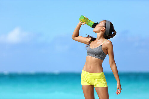 Mantenersi idratati: ragazza beve su una spiaggia