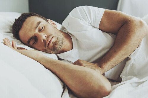 Sonno brucia grassi: uomo dorme su lenzuola bianche
