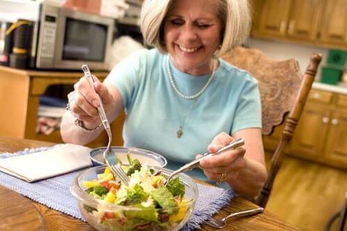 Donna non più giovane mangia un'insalata.