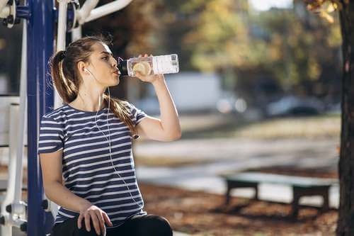 Idratazione durante lo sport: ragazza con maglietta a righe beve