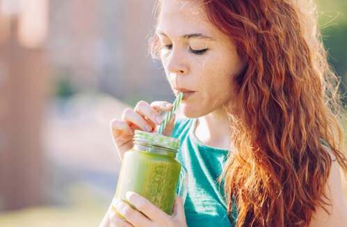 Proteine vegetali: ragazza beve un succo verde