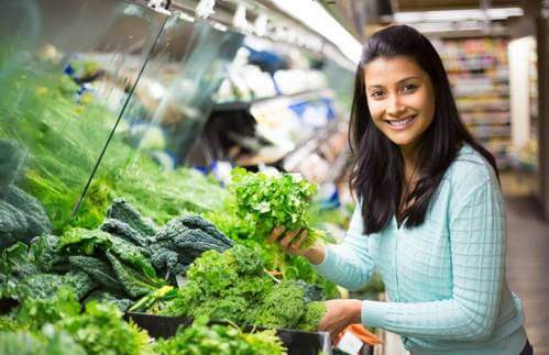 Donna sceglie delle verdure a foglia verde al supermercato.