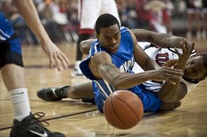 Basketballspiller har blitt taklet og befinner seg på gulvet.