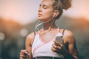 Kvinne lytter til musikk mens hun trener utendørs.