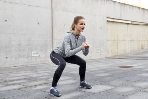 Kvinne trener knebøy utendørs.