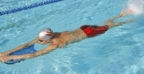 Mann svømmer med brett