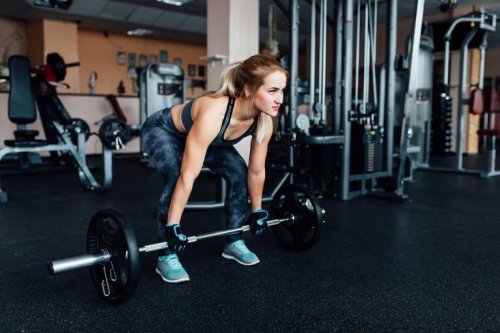 kvinne trener markløft for å løfte mer vekt på treningssenteret