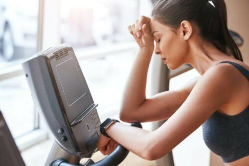 Kvinne med muskelutmattelse som prøver å trene.
